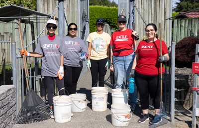 Five members of Women of SU holding rakes and buckets at a volunteer event.