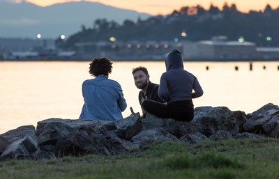 A group of people sitting on rocks by water.