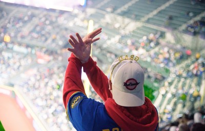 A person in a baseball cap raising their hands.