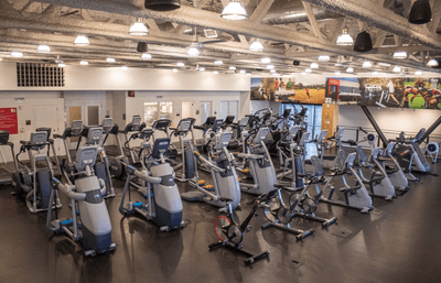 an open gym space with multiple elipticals
