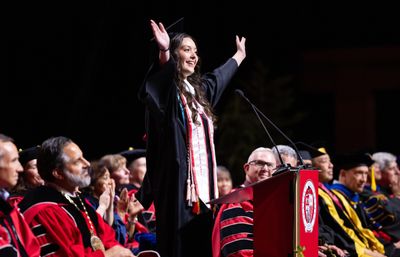 Undergraduate speaker raises her hands during her speech at the Undergraduate Commencement ceremony