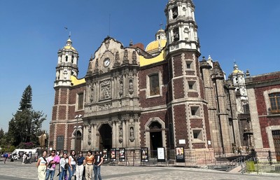 Students posing by a building with Pueblo architecture