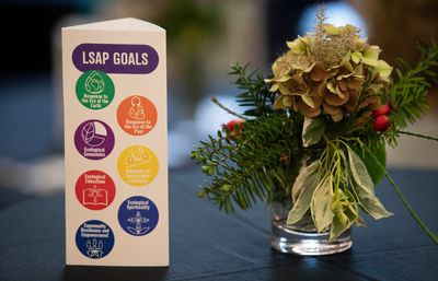 Photo of a flayer of each of the 7 Laudato Si' goals on the left and a vase with flowers on the right