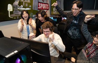 Students gathered around a gaming computer cheering