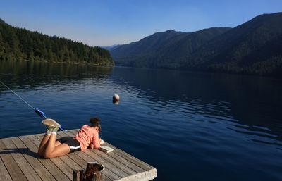 Girl sitting on dock by the water journaling