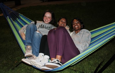 three students sitting together on a hammock