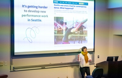 Person presenting at symposium in front of screen