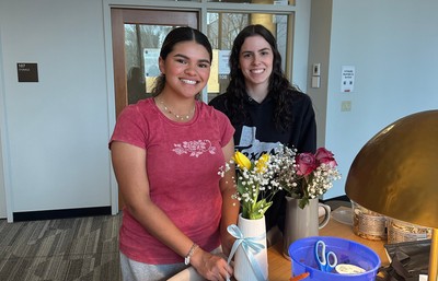 Students posing in front of their flowers in vases