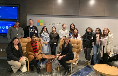 A group of students visiting Microsoft, with a digital screen in the background