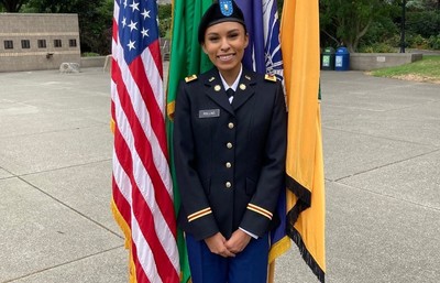 A woman in uniform standing next to two flags.