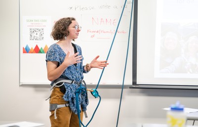 Student in front of whiteboard with climbing rope attached to them presenting