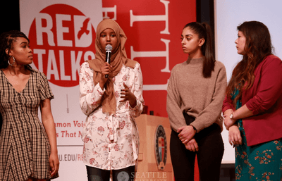 Four students speaking on a stage.