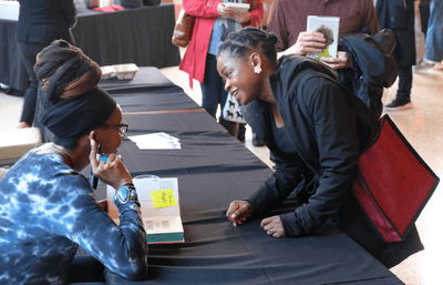 Doctor Nnedi Okorafor talking with a student while signing books.