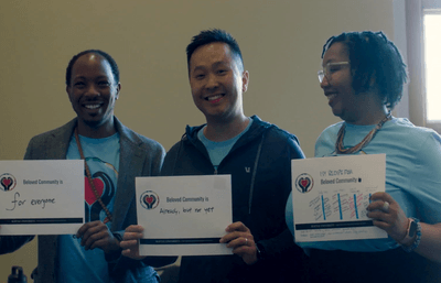 Three faculty members holding signs smiling