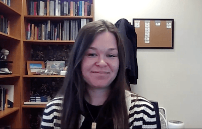 Dr. Joyner-Carpanini smiling on Zoom in front of bookshelf in office