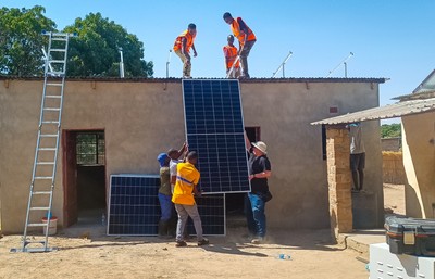 SU Electrical and Computer Engineering alumnus Daniel Nausner (’14) (right) helps install  solar panels on an “energy kiosk” in Cheeba, Zambia.  The energy kiosk powers a grocery store, tailoring business, barbershop, and more.