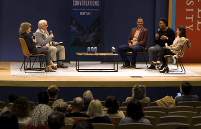 Joni Balter and Larry Hubbell interview three city council members on stage.