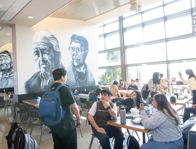 A group of people sitting at tables in a cafeteria.