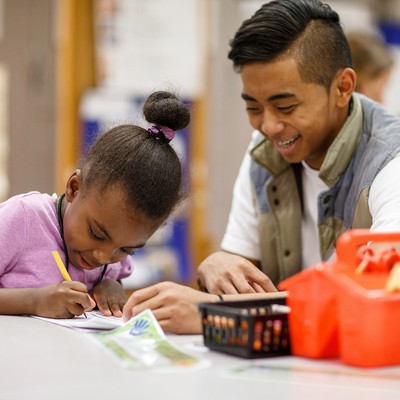 A man and a young girl working together at a table.