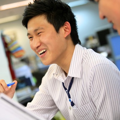 A man laughing while holding a pen.