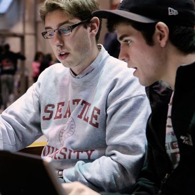 Two students looking at a laptop inside a busy campus building