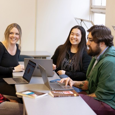 Three students at a table with laptops in a Public Administration Program class with Larry Hubbell