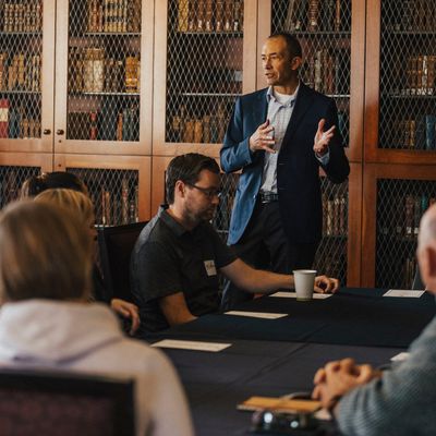 A professor gesturing and talking in a wood-paneled library reading room