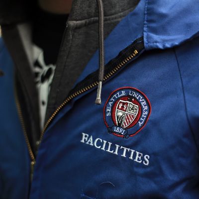 Close-up  of person wearing blue jacket with Facilities written on left chest and SU seal logo.