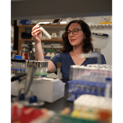 A photograph of Carolyn Stenbak in the lab looking at a test tube.