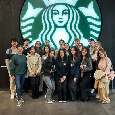Students standing in front of Starbucks logo on a company tour