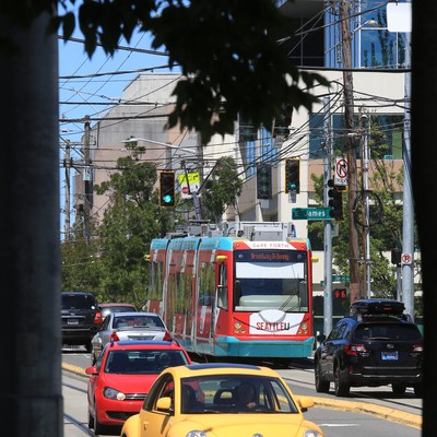 A yellow car is driving down a street in a city.
