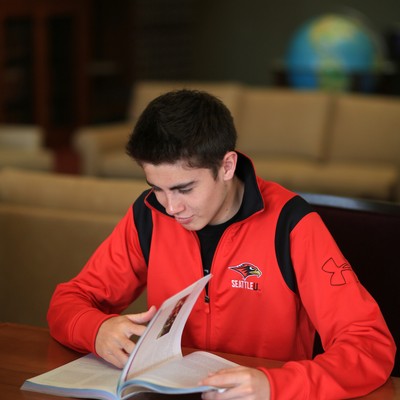 Student sitting in campus library reading a book