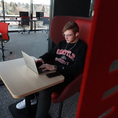 A student sits in a chair with a laptop.