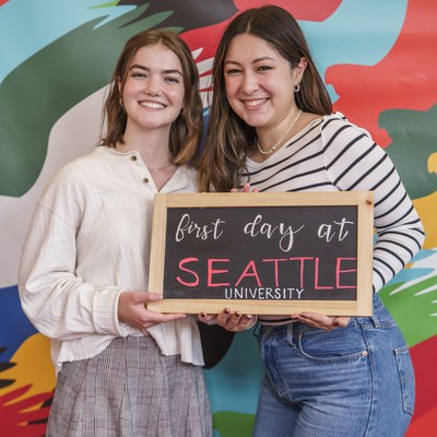 Two students smiling and holding a chalkboard sign that reads: First Day at Seattle University