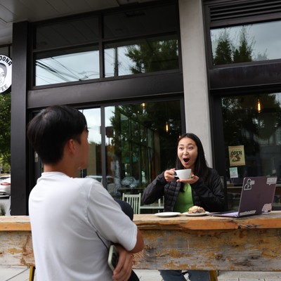 Two students drinking coffee outside boon boona, a cafe close to campus
