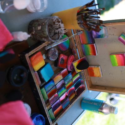 a box of multi colored paints on a table with paintbrushes