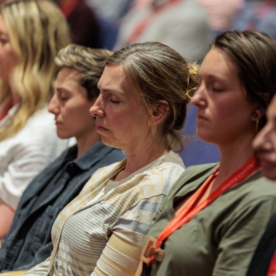 Women sitting at a gathering with their eyes closed