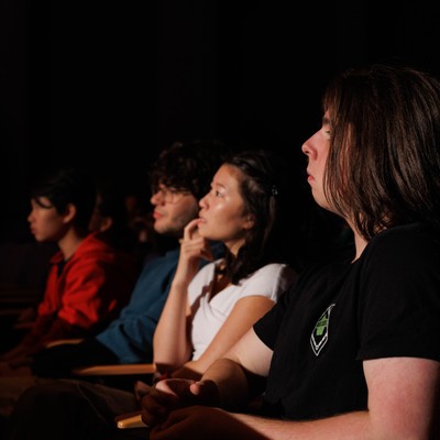 A row of guests in Pigott Auditorium watching a presentation