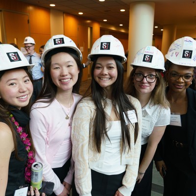 Students in white SU hardhats smile