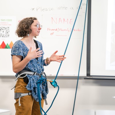 Student in front of whiteboard with climbing rope attached to them presenting
