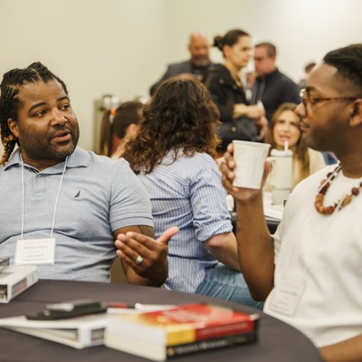 Two faculty members sitting at a table engaging in conversation.