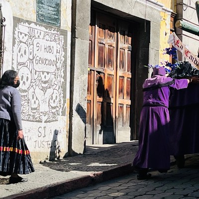 Photo of artwork on wall and people in procession