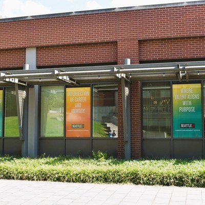 Pigott Pavilion brick building with 3 colorful window clings: Text Career Exploration And Discovery, Intersection of Career And Identity and Where Talent Aligns with Purpose
