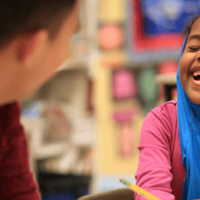 Education and teaching - School child laughing with teacher in a classroom