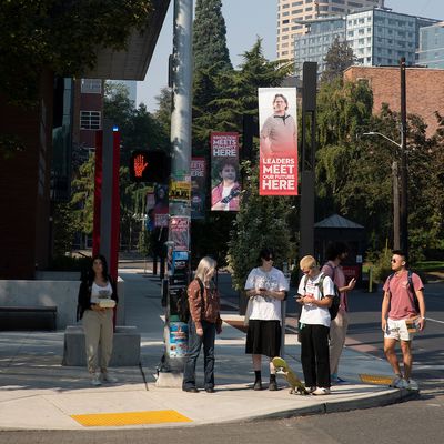 group of people standing on the corner of the main entrance of campus