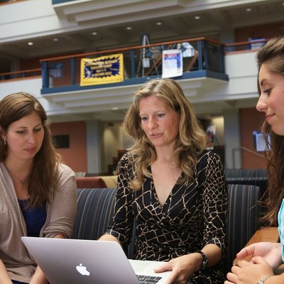 Three students look at a laptop