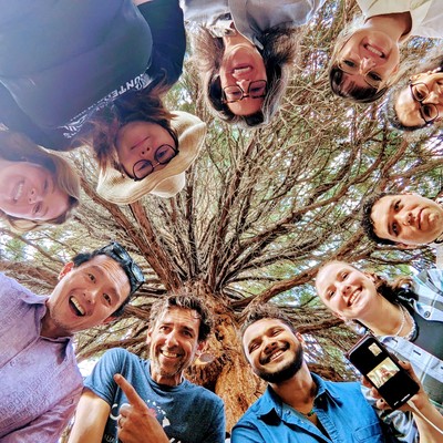 Students smile in circle looking down at camera on ground