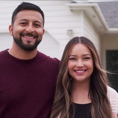 A couple posing in front of a house