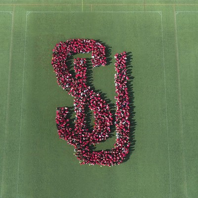 aerial of people forming the SU logo on a grass field