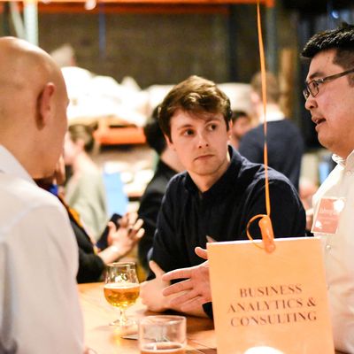 Three men engaged in conversation at a social event with drinks on the table.